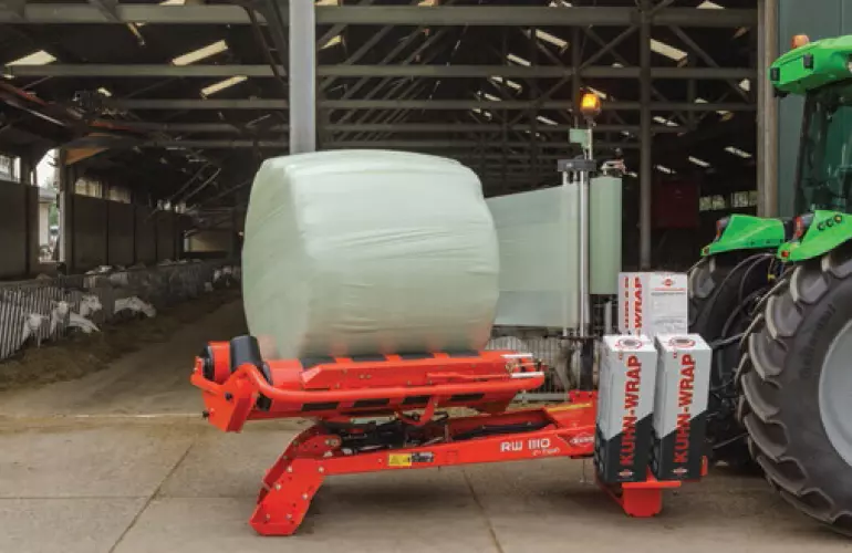 RW 1110 owijający okrągłą belę przed oborą dla kóz.