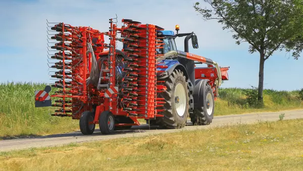 Zestaw wysiewający podczas transportu drogowego, składający się z brony wirnikowej HR 4530 RCS i belki wysiewającej BTFR 4530