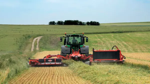 Kosiarka ze zgniataczem i transporterem pokosu podczas pracy wzdłuż granicy łąki z życicą.