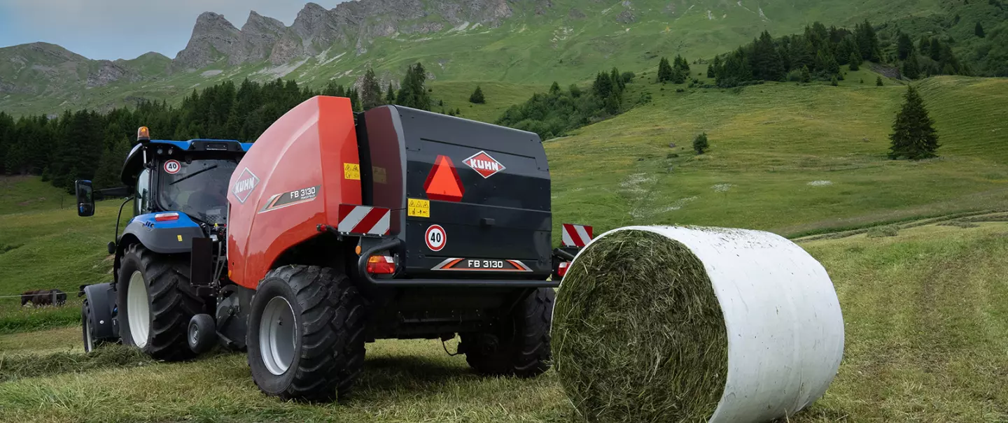 Stałokomorowa prasa zwijająca KUHN FB 3130 z wiązaniem folią produkująca okrągłe bele w górach