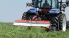 Zgniatacz pokosu TC 320 podczas pracy w wysokiej trawie z traktorem na podwójnych kołach.